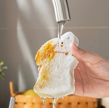 Load image into Gallery viewer, Person holding a piece of wood pulp sponge under running water from a faucet.