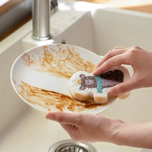 Load image into Gallery viewer, Person scrubbing a dirty plate with a bear design sponge in a kitchen sink.
